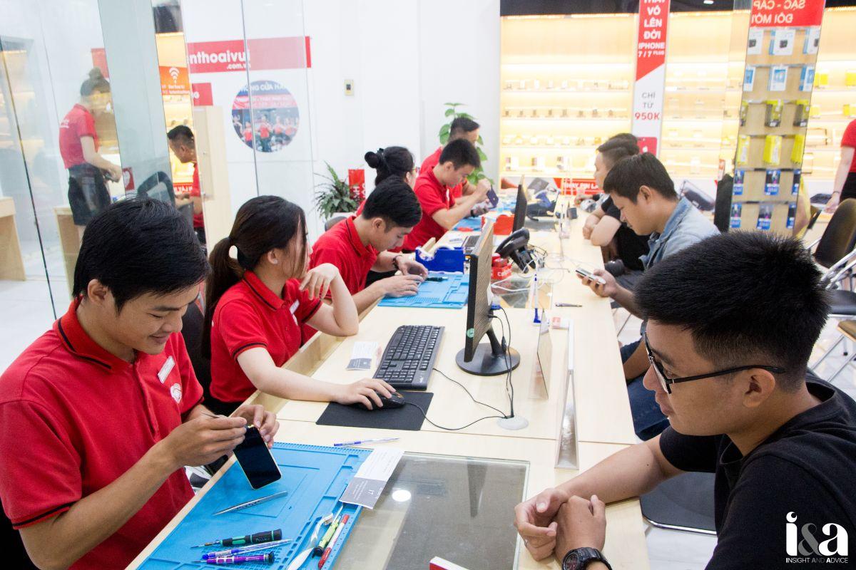 Kỹ thuật viên Điện Thoại Vui đang sửa chữa điện thoại tại trung tâm, khách hàng ngồi chờ 
